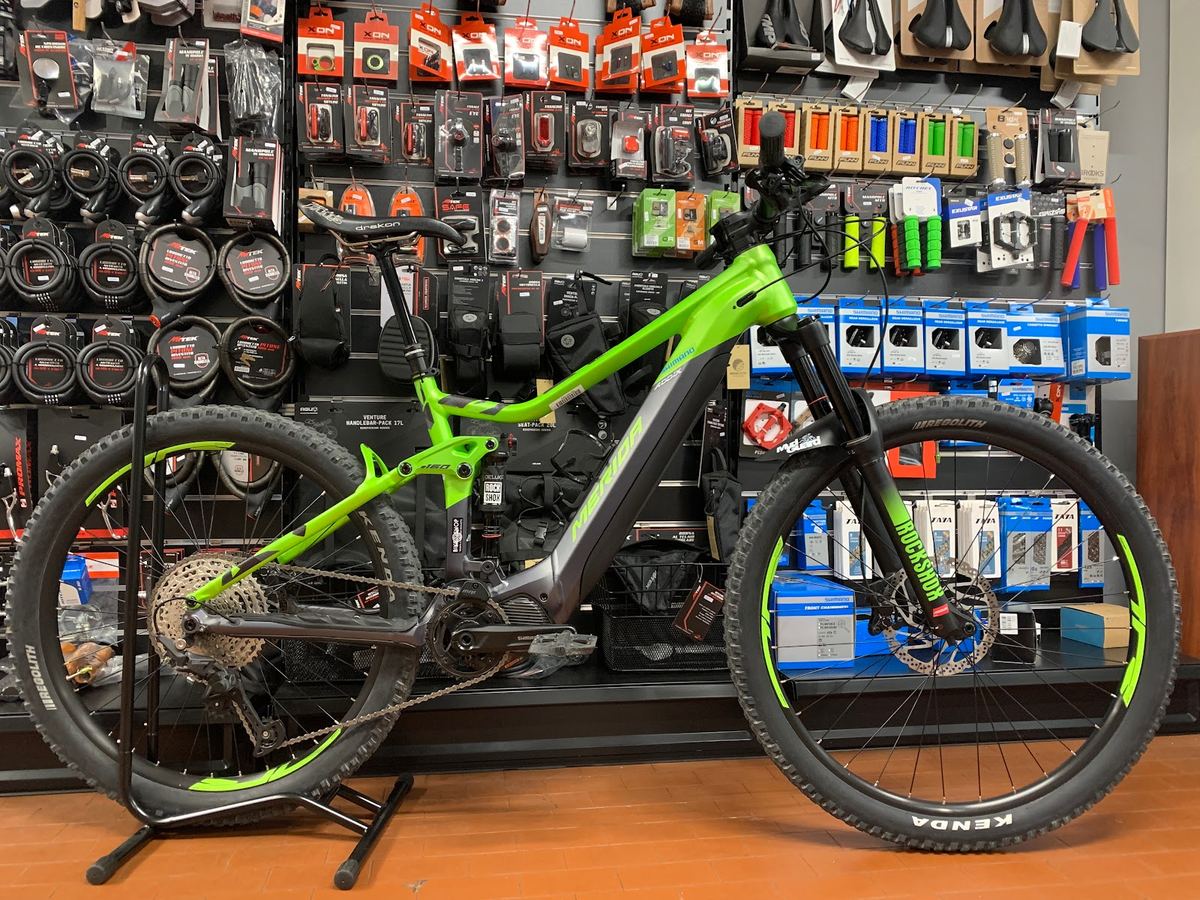 Mountain bike elettrica biammortizzata verde e nera sul cavalletto